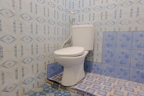 A bathroom with a toilet, patterned tiles, and a shower area. - Spot On 1971 Hotel Dewi (Peterongan)
