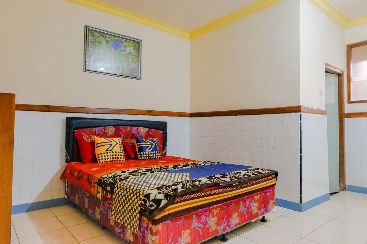 Un dormitorio con cama, una puerta y un cuadro colgado en la pared.