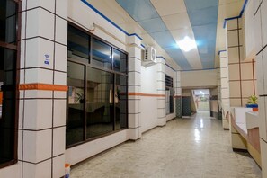 Un couloir aux murs recouverts de carreaux, avec un ventilateur de plafond et une fenêtre.