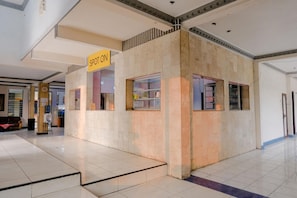 A spot-on kiosk in a spacious indoor area with tiled floors and a high ceiling. - Spot On 1971 Hotel Dewi (Peterongan)