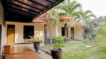 A covered outdoor area with a tiled floor, a wooden door, and a small seating area with chairs.