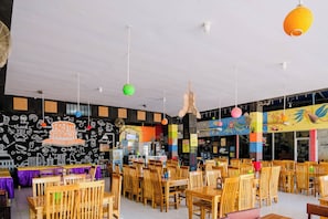 A restaurant with wooden tables and chairs, a blackboard wall with doodles, and hanging spherical lights. - Spot On 1958 Asembagus Family (Asembagus)