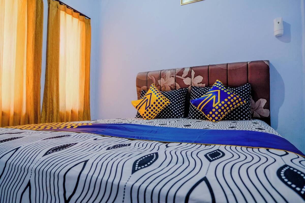 A bed with patterned bedding, a floral headboard, and decorative pillows.