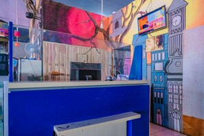 Una habitación con mostrador azul, un armario de madera y un mural en la pared.