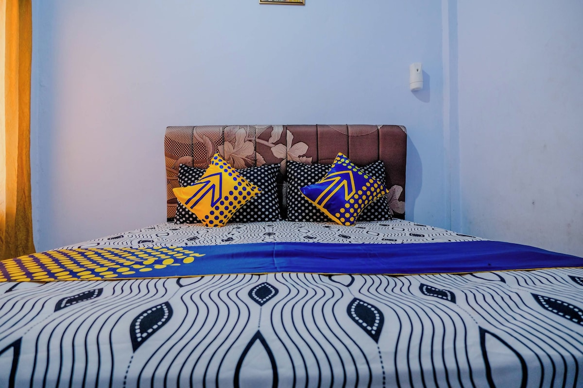 A bed with patterned bedding, a floral headboard, and two decorative pillows.