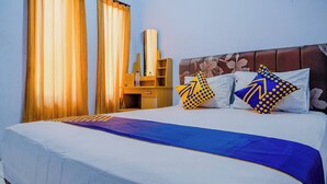 A hotel room with a bed, curtains, a wooden desk, and a mirror. - Spot On 1958 Asembagus Family (Asembagus)