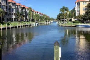 A canal with buildings on either side, a dock with a boat, and a clear sky.
