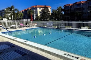 A swimming pool with a white fence, lounge chairs, and a building in the background. - Across from Beach, Stunning Canal Views, Age 55 up (Siesta Key)