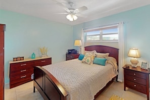 A bedroom with a bed, nightstands, a dresser, a ceiling fan, and a window with curtains. - Across from Beach, Stunning Canal Views, Age 55 up (Siesta Key)