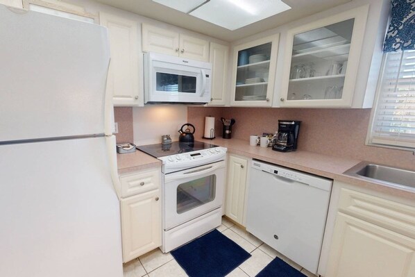 A compact kitchen with white appliances, including a refrigerator, microwave, stove, and dishwasher. - Across from Beach, Stunning Canal Views, Age 55 up (Siesta Key)