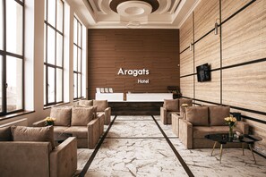 A modern hotel lobby with a reception desk, sofas, and a marble floor. - Aragats Hotel (Aragats)