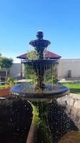 Una fuente de varios niveles con agua cayendo, sobre un cielo azul despejado.