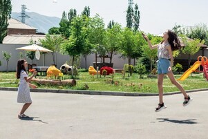 Un parque infantil con toboganes y columpios, una cancha de tenis y un edificio al fondo.