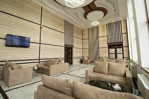 Un vestíbulo moderno con sofás color beige, un televisor de pantalla plana y un suelo con diseño de mármol.