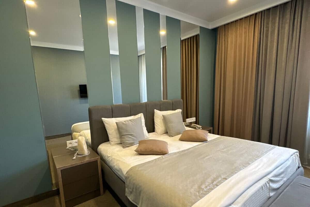 A modern hotel room with a large bed, a bedside table, and a nightstand.