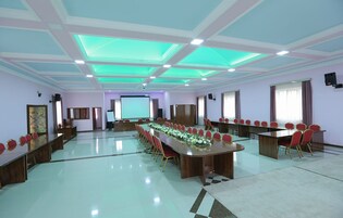 Una sala de conferencias con una larga mesa, sillas rojas y una pantalla para proyector.