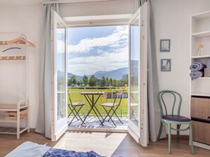 Een kamer met balkon, een bed, een stoel en een tafel.
