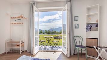 Ein Zimmer mit Bett, Stuhl, Tisch, einem Balkon mit Bergblick und einem Kleiderschrank.