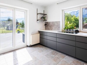 Une cuisine moderne dotée d’une grande fenêtre, d’une cuisinière encastrée et d’un plan de travail.