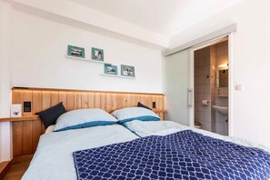 Une chambre à coucher avec une tête de lit en bois, deux oreillers, une couvre-lit à motifs et un mur orné de trois tableaux encadrés.