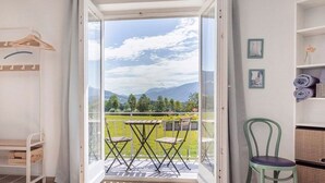 Una habitación con balcón, cama, silla y mesa.