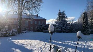 A snow-covered landscape with a red building, snow-covered trees, and a clear sky.