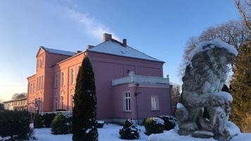 Ein pinkfarbenes Gebäude mit einer schneebedeckten Statue im Vordergrund.