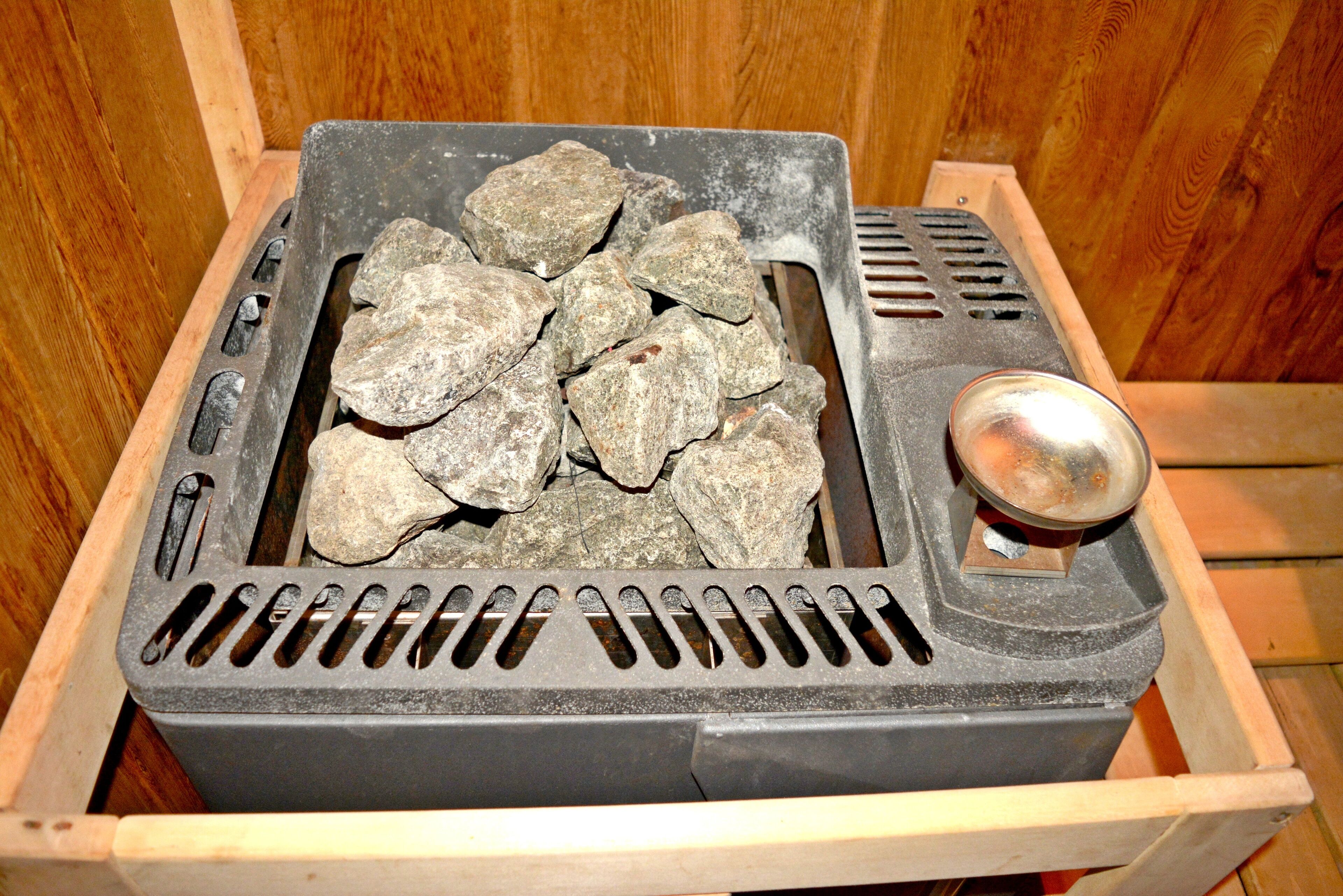 Una parrilla portátil con piedras y un asa metálica, probablemente para cocinar al aire libre.