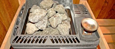 Una parrilla portátil con piedras y un asa metálica, probablemente para cocinar al aire libre.