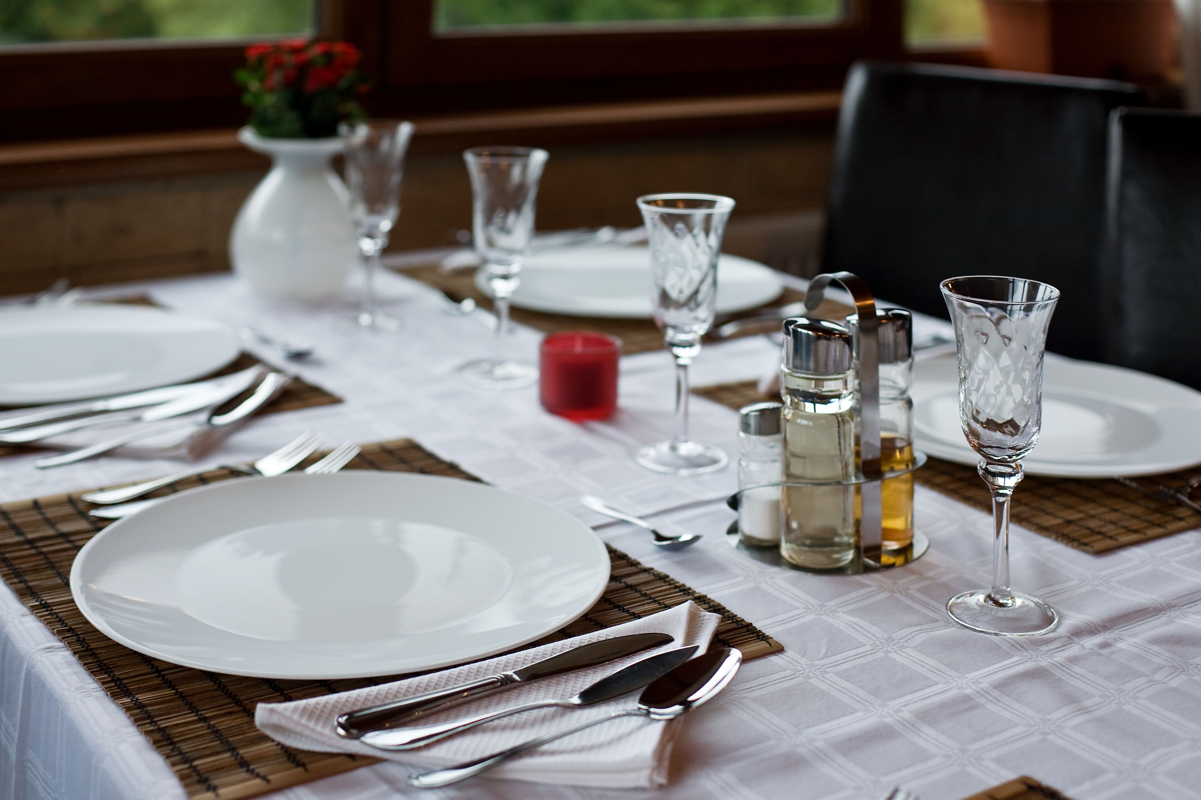A table set for dining with plates, cutlery, glasses, and a candle.