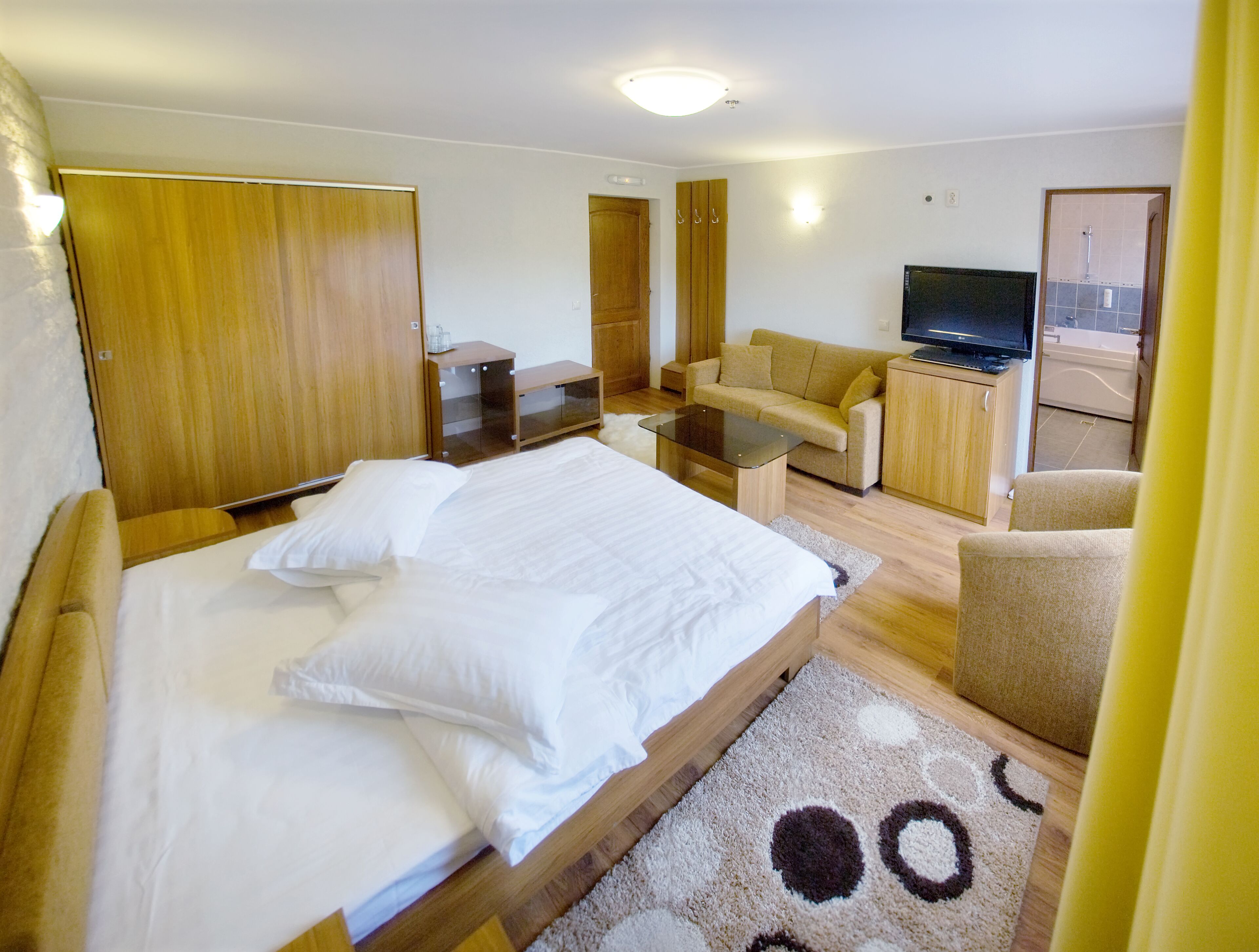 Una habitación de hotel con una cama, un sofá, un televisor y un escritorio pequeño.