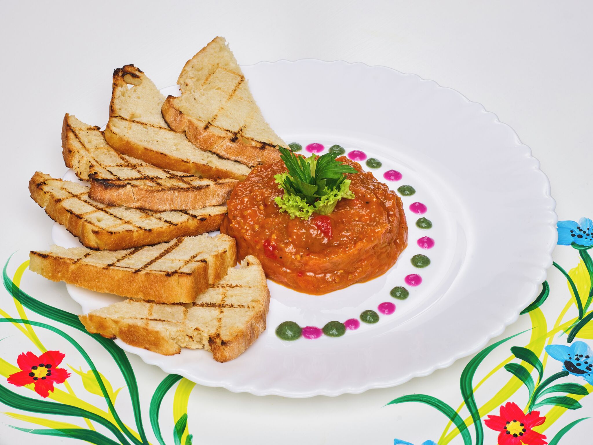 A plate with grilled bread and a tomato-based dip, garnished with parsley.