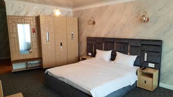 Habitación de hotel con una cama grande, un armario con puertas de espejo, una mesita de noche y un buró.