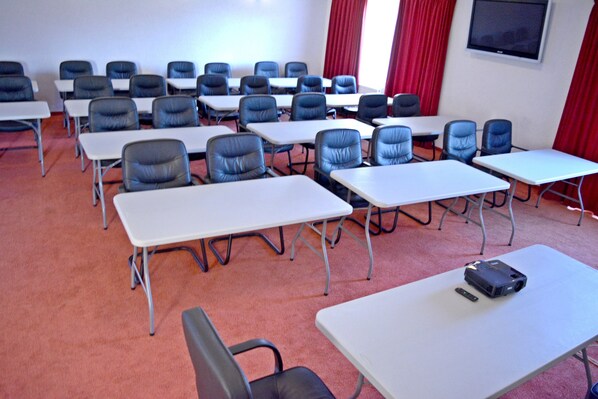 A conference room with rows of tables and chairs, a projector, and a screen on the wall. - Resort EuroPark (Fundata)