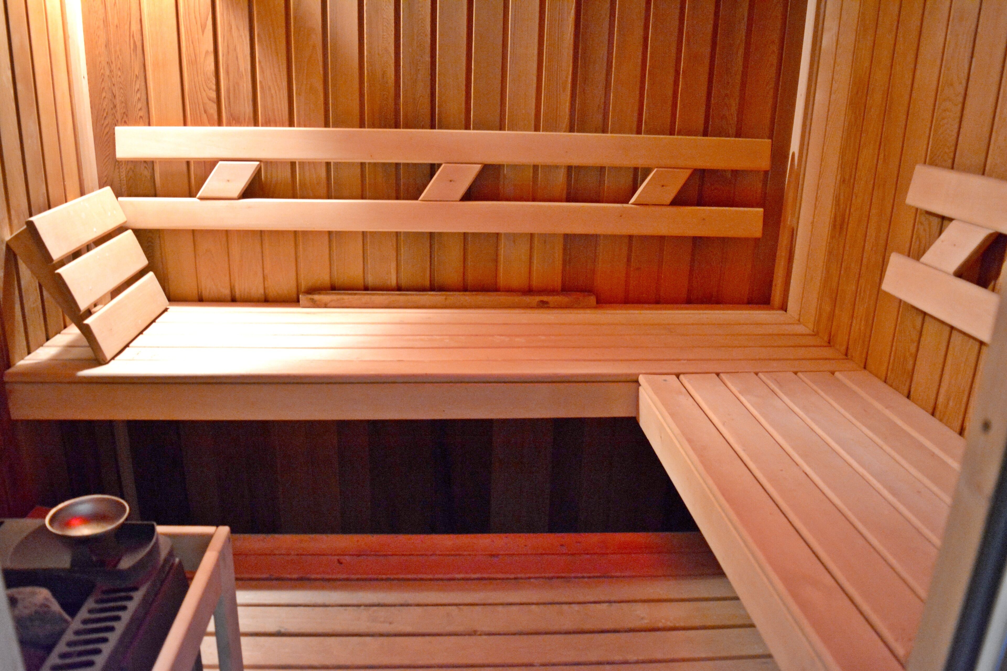 Una sauna con bancos de madera y un asiento.