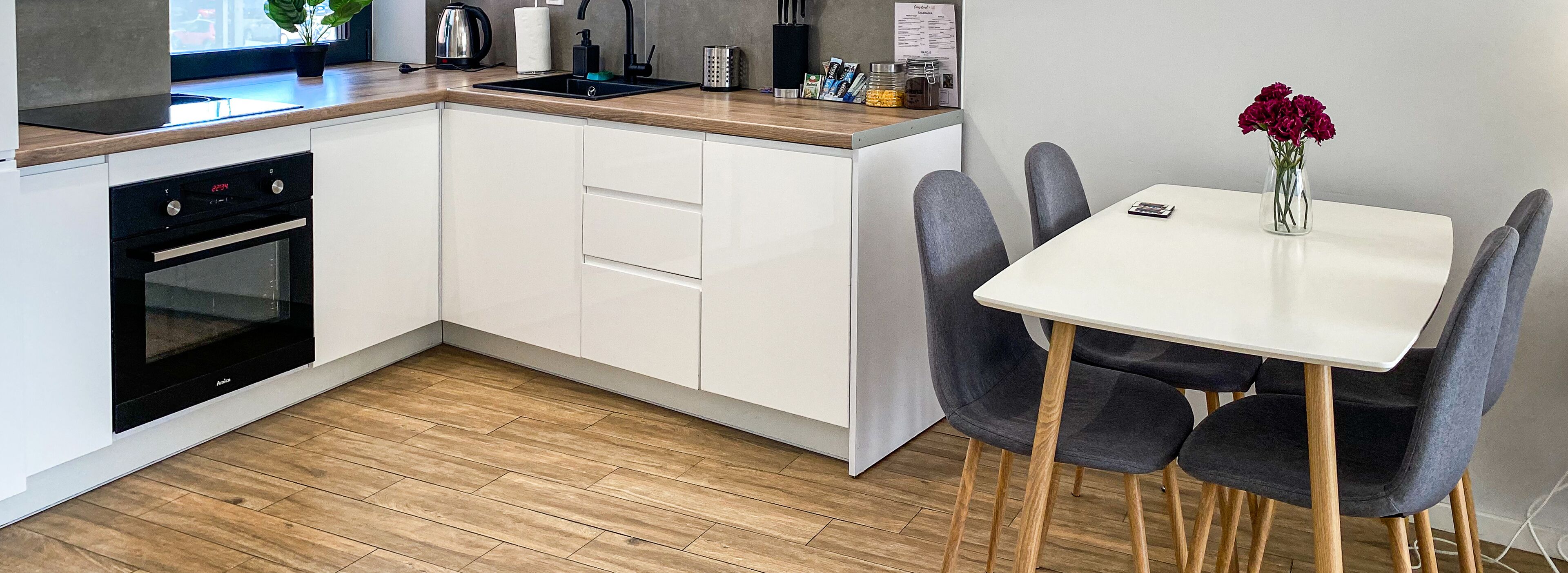 A compact kitchen with a built-in oven, a sink, and a dining area with a table and chairs.