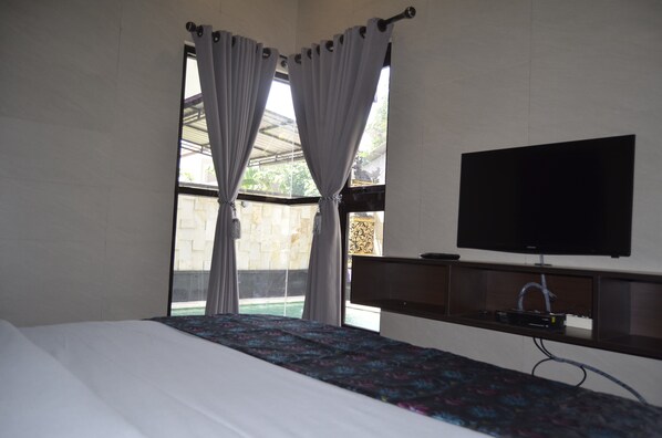 A hotel room with a bed, a TV mounted on the wall, and a window with curtains.