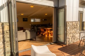 An open sliding glass door leading into a living area with a sofa, a dining table, and chairs. - THE PERFECT GETAWAY - Sunny & Spacious WIFI FREE (Twizel)