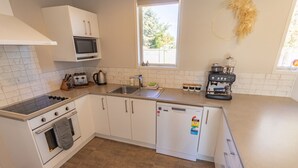 Eine kleine Küche mit Herd, Mikrowelle, Spüle und kleinem Kühlschrank.