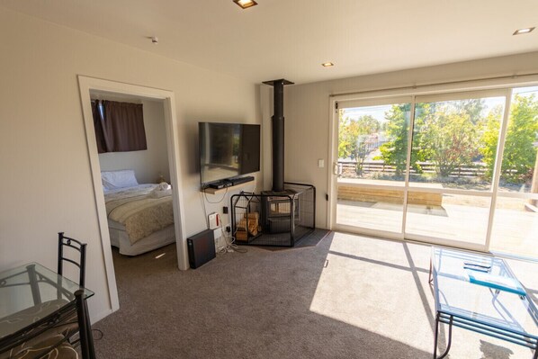 Une chambre moderne équipée d’un lit, d’une télévision, d’une cheminée et d’une porte-fenêtre coulissante donnant sur une terrasse.
