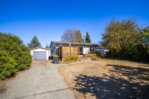 A single-story house with a front porch, a garage, and a small shed.
