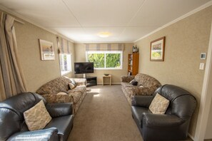 A living room with two patterned sofas, a television, a small table, and a bookshelf.