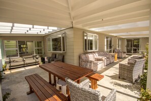 Une terrasse couverte avec une table en bois, des chaises en osier et un canapé.