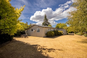 A single-story house with a covered patio, surrounded by trees and a clear sky.