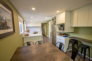 A compact kitchen with a dining area, featuring a refrigerator, microwave, and a small bar counter with stools.