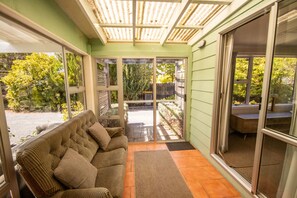 A cozy room with a sofa, a sliding glass door leading to an outdoor area, and a wooden ceiling structure.