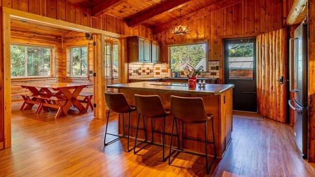 Een houten hut interieur met een keuken, eethoek en barstoelen.