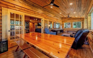 Interior de madera con una gran mesa de comedor, sillas azules y una mesa de billar.