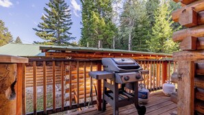 Una terraza de madera con una parrilla y tanque de propano.