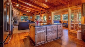 Een chalet met een stenen openhaard, houten plafond en een groot eiland met lades.